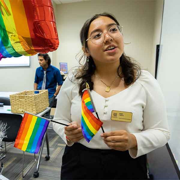 ksu student holding pride flags in the LGBTQ center.