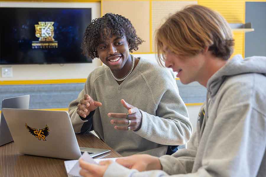 Two KSU students sitting at a table talking