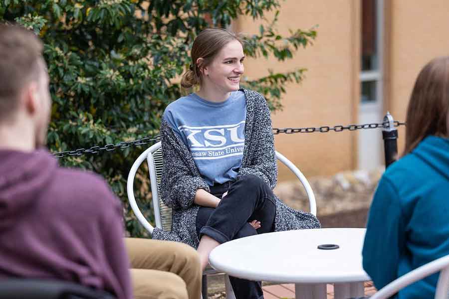 Student wearing KSU t-shirt sitting with group of students.