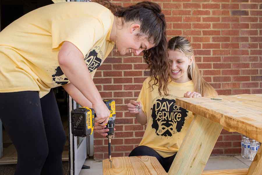 KSU Students at day of service working on a wooden bench.