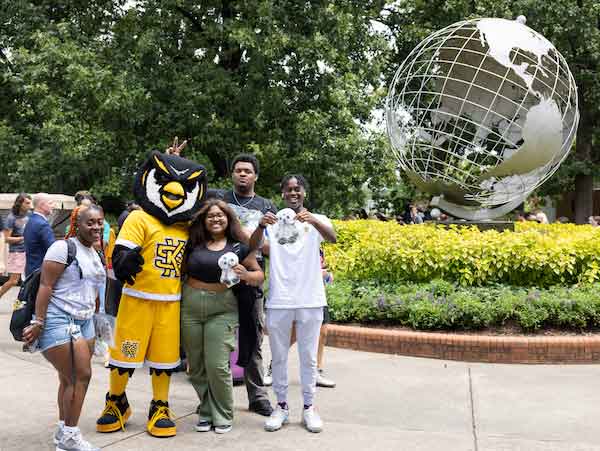 ksu students at the marietta campus by the globe taking a picture with scrappy.