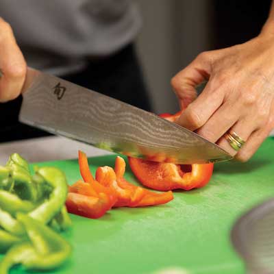 close up of chef using knife to cut peppers 