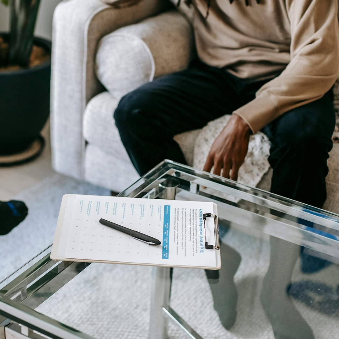 Male during psychologist appointment sitting with evalaution papers on table