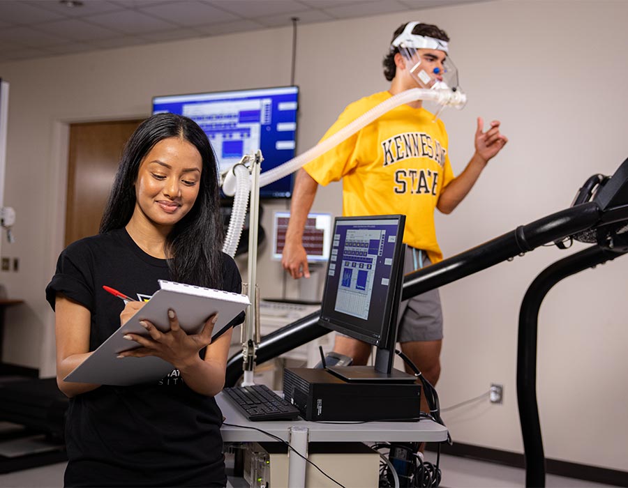 ksu student monitoring another student work out on a treadmill.