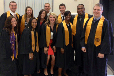 group photo of ksu students in their graduation gowns and scarfs.