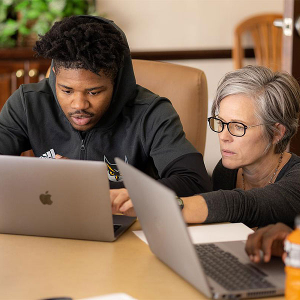 ksu student and faculty looking at laptop