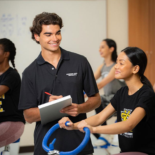 ksu student working out while a man takes notes