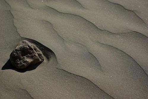 craggy-textured rock is on the rippled sandy shore of a beach. Image is titled “Beach on the Chang Jiang (Yangtze)” by Eul Mulot