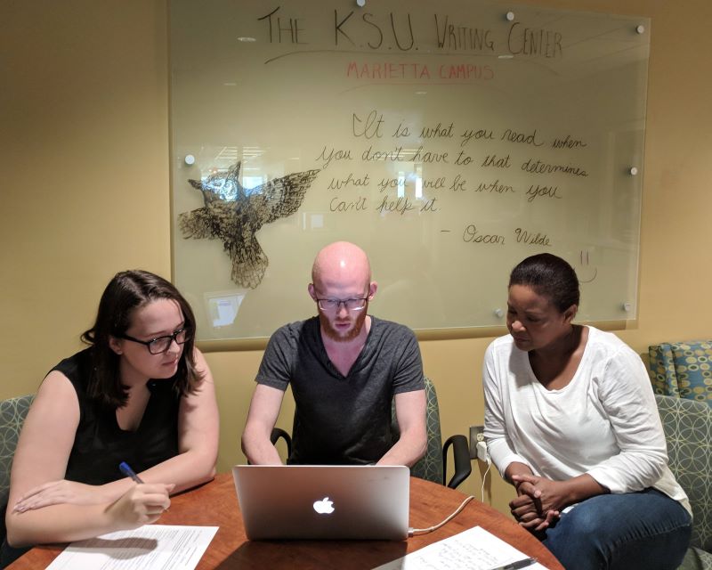 KSU graduate students in the Writing Center, using a laptop.