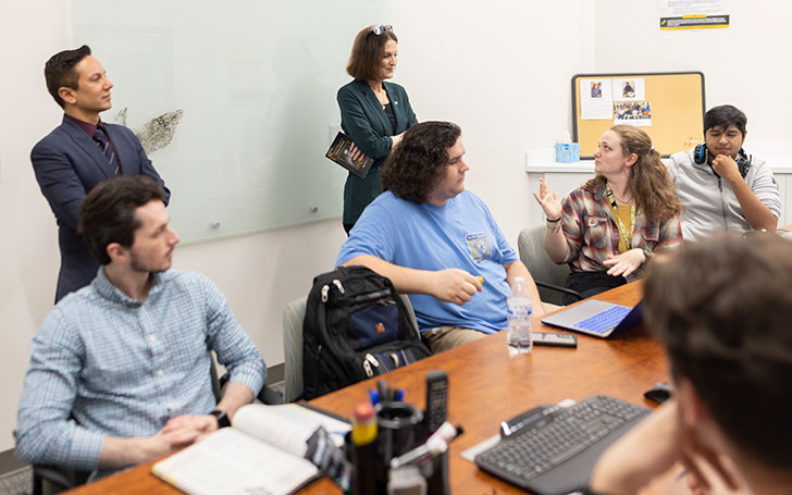 A group of people engaged in discussion around a table in a conference room.